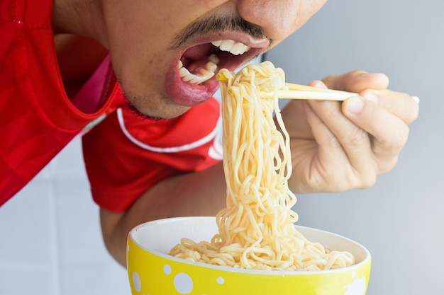 Un uomo che si diverte a mangiare spaghetti istantanei