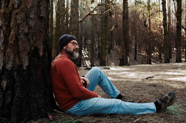 Un uomo che si rilassa seduto a terra in mezzo ai boschi verdi e all'aperto si rilassa attività ricreativa Le persone e l'amore si sentono con il parco naturale Benessere stile di vita alternativo