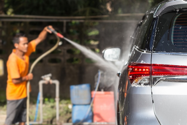 Un uomo che spruzza l&#39;idropulitrice per l&#39;autolavaggio nel negozio di cura dell&#39;auto