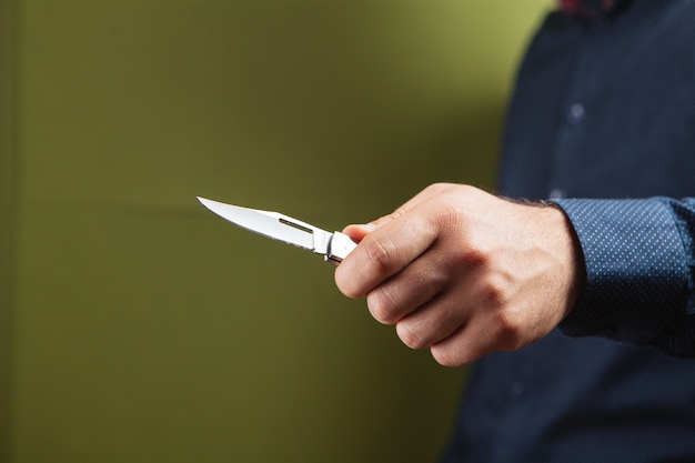 Un uomo che tiene un coltello a mano su uno sfondo verde