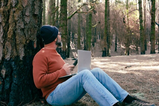 Un uomo che utilizza la connessione tecnologica nei boschi del parco naturale Lavoratore remoto Piccole attività di viaggio Stile di vita Persone che lavorano nell'ufficio alternativo della natura Piccole imprese Viaggiatori vita lavorativa