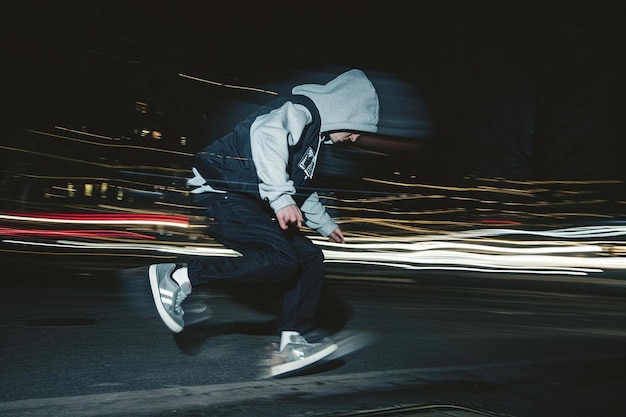 un uomo che va su uno skateboard per una strada di notte