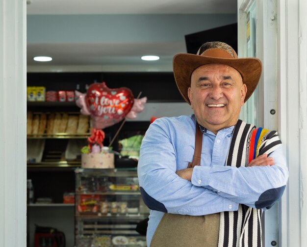 Un uomo colombiano imprenditore appoggiato alla porta del suo caffè