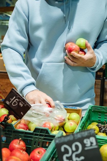 Un uomo compra cibo Un cliente maschio sceglie le mele prendendo i prodotti dagli scaffali