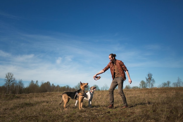 Un uomo con due cani che cammina su un prato soleggiato