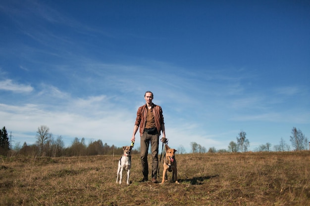 Un uomo con due cani che cammina su un prato soleggiato