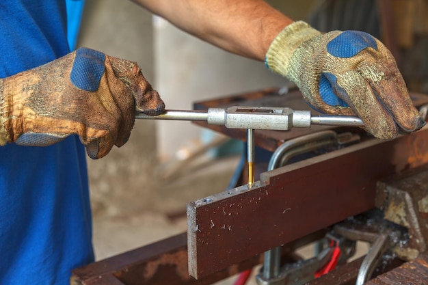 Un uomo con guanti protettivi sulle mani taglia un filo di metallo per una futura connessione