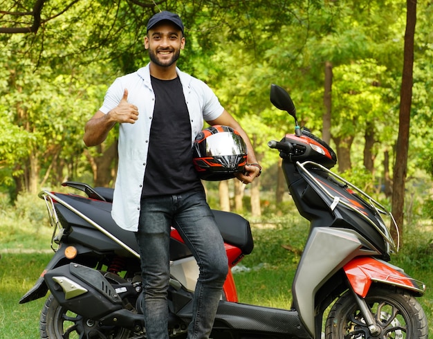 Un uomo con il suo nuovo scooter e casco che rinuncia all'immagine a grandezza naturale