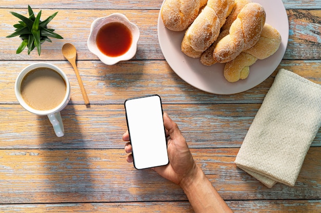 Un uomo con in mano una tazza di caffè nero e un bicchiere di succo d'arancia Croissant pane