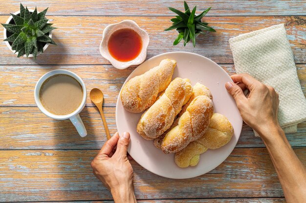 Un uomo con in mano una tazza di caffè nero e un bicchiere di succo d'arancia Croissant pane