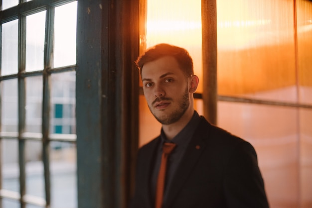 Un uomo con la barba e gli occhiali da sole in un abito grigio posa per strada per pubblicizzare l'abbigliamento maschile.