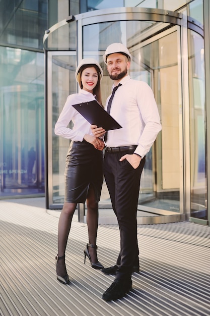 Un uomo con la barba e una donna in abiti d'affari sta studiando disegni e documenti per un nuovo progetto