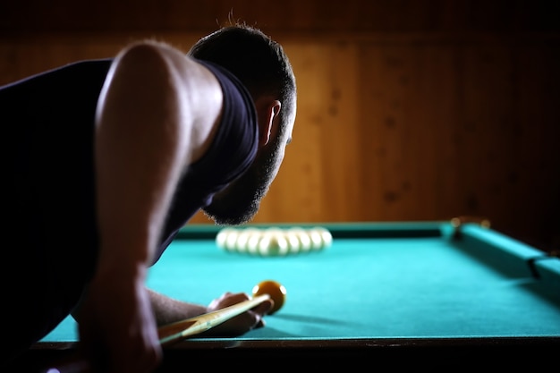 Un uomo con la barba gioca a biliardo. Festa in piscina da 12 piedi. Biliardo nel gioco del club per gli uomini. Un uomo con una stecca rompe la piramide.