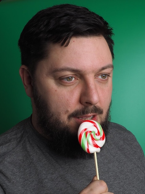 Un uomo con la barba sta mangiando un lecca-lecca.