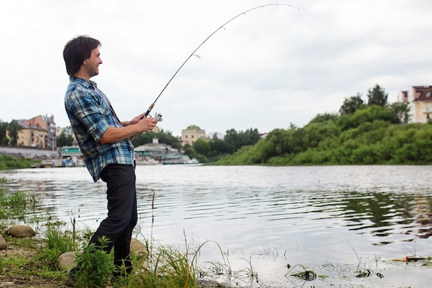 Un uomo con la barba sta pescando per la filatura nel fiume