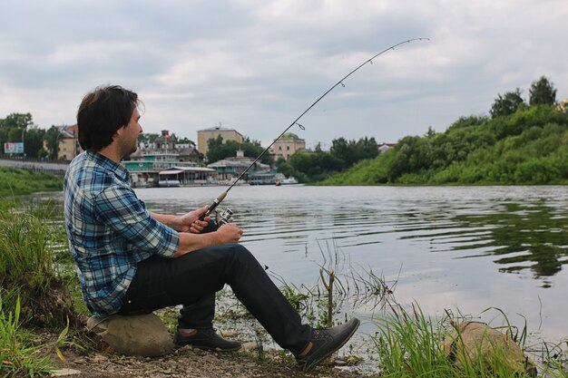 Un uomo con la barba sta pescando per la filatura nel fiume