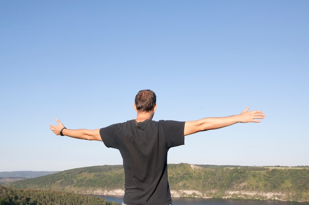 Un uomo con le braccia tese contro il cielo e la natura. Recupero, divertimento, concetto di equilibrio