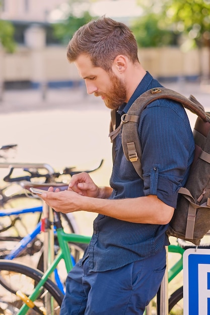 Un uomo con lo smartphone vicino al parcheggio delle biciclette.