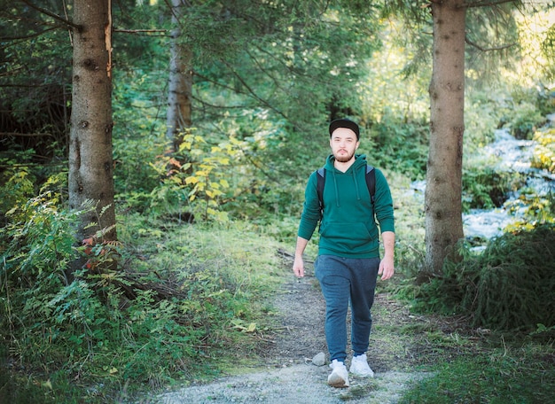 Un uomo con lo zaino cammina nella foresta autunnale. Camminare da soli lungo i sentieri dei boschi autunnali. Concetto di viaggio.