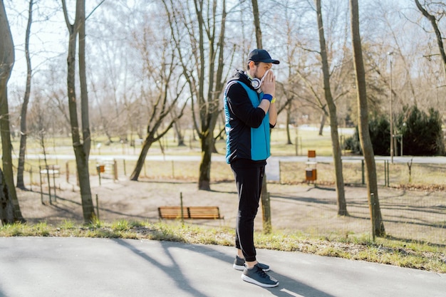 Un uomo con un'allergia ai pollini sta fuori in un parco un atleta smette di correre