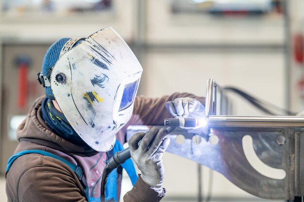 Un uomo con un'attrezzatura di protezione personale sta saldando metallo in una fabbrica