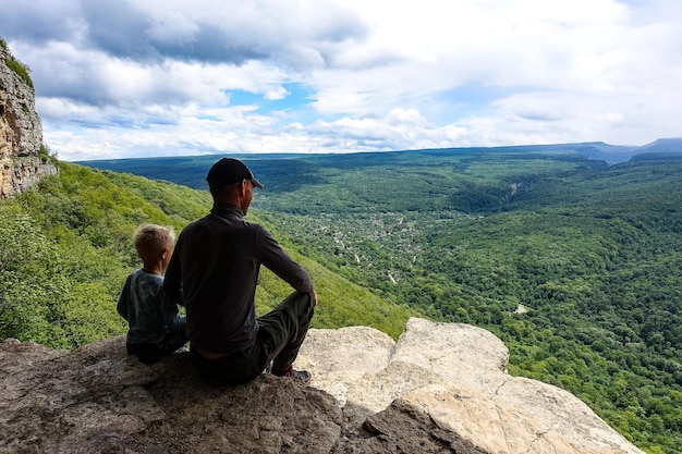 Un uomo con un bambino sullo sfondo del paesaggio delle montagne del Caucaso Eagle Rocks