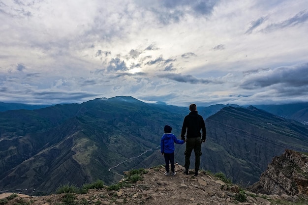 Un uomo con un bambino sullo sfondo di una vista sulle montagne dall'antico villaggio di Goor Russia Daghestan 2021