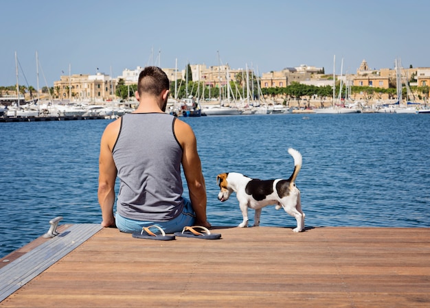 Un uomo con un cane che cammina sul molo galleggiante