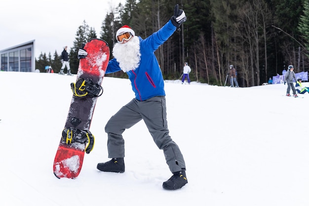 un uomo con un cappello da Babbo Natale con uno snowboard in una stazione sciistica.