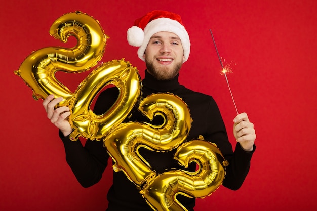 Un uomo con un cappello da Babbo Natale tiene in mano i numeri 2022 e una stella filante