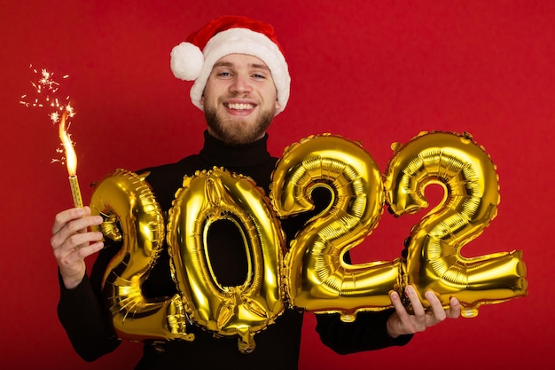 Un uomo con un cappello da Babbo Natale tiene in mano i numeri 2022 e una stella filante