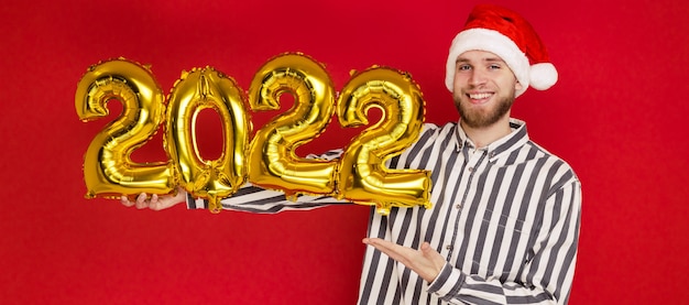 Un uomo con un cappello di Natale tiene in mano i numeri 2022. Il nuovo anno sta arrivando