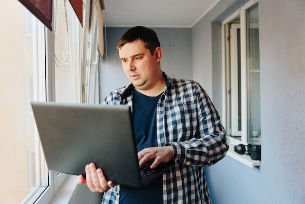 un uomo con un laptop nero nelle sue mani lavora a casa