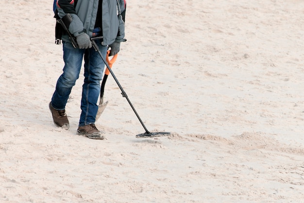 Un uomo con un metal detector è alla ricerca di gioielli.