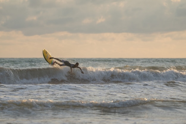 Un uomo con un surf tra le mani in riva al mare