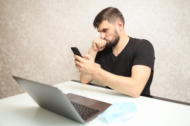 un uomo con un telefono in mano è seduto a un laptop