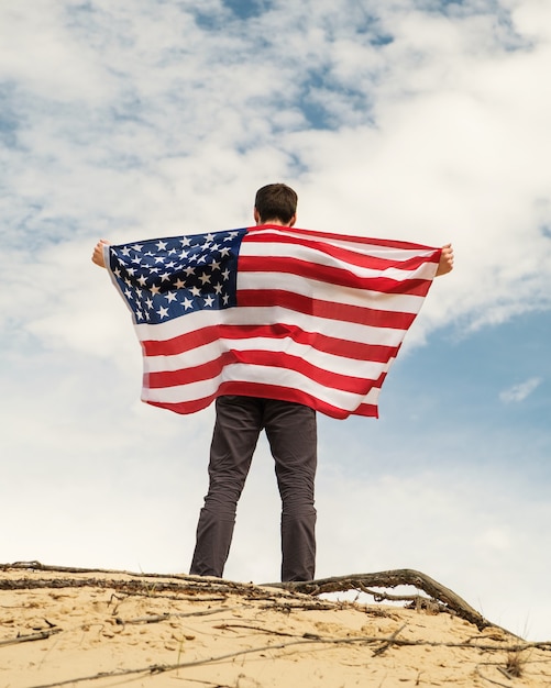 Un uomo con una bandiera americana si erge sui cieli di sabbia sullo sfondo