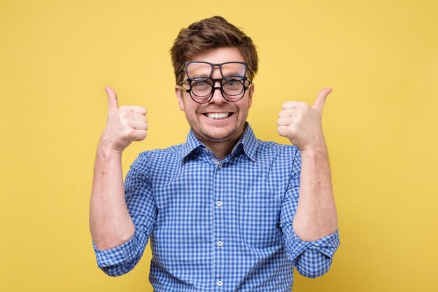 Un uomo con una camicia blu prova a selezionare gli occhiali per la visione mostrando il pollice in su approvando la scelta