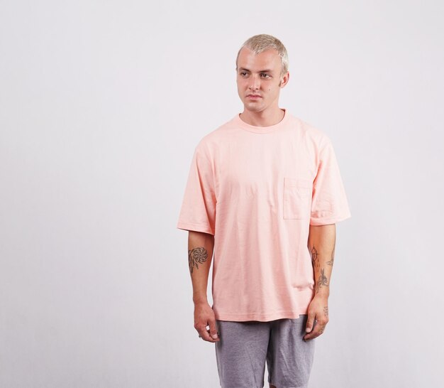 Un uomo con una camicia rosa è in piedi davanti a uno sfondo bianco
