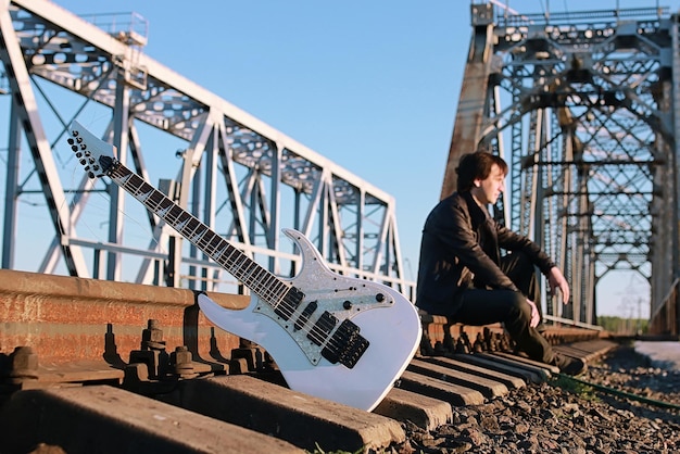 Un uomo con una chitarra elettrica nel paesaggio industriale all'aperto