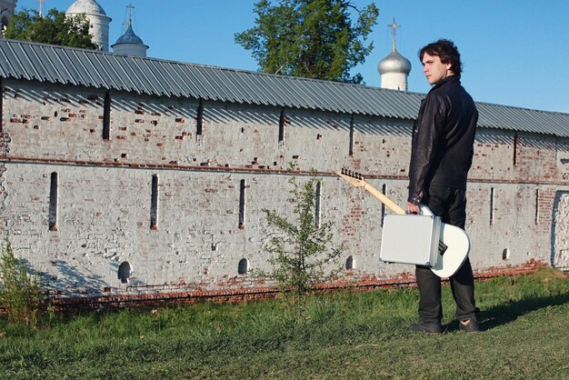 un uomo con una chitarra elettrica nel paesaggio industriale all'aperto