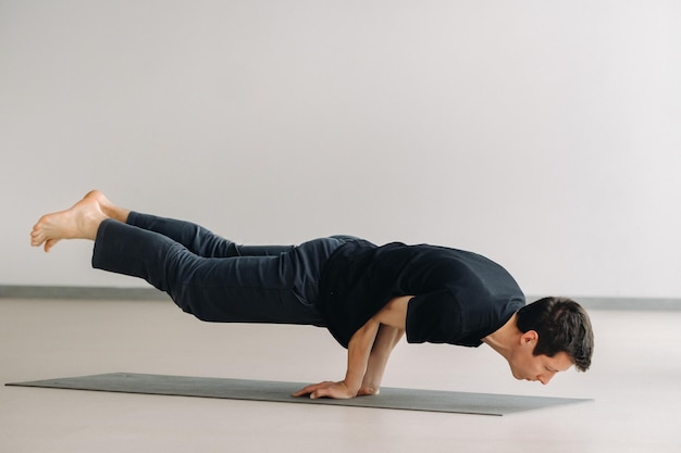 Un uomo con una maglietta nera si allena sdraiato facendo stretching in palestra