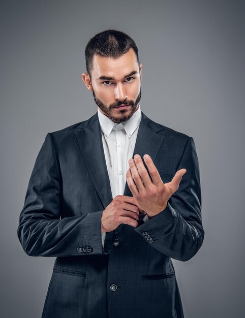 Un uomo d'affari alla moda in un vestito isolato su sfondo grigio.