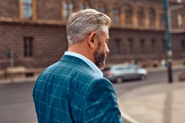 Un uomo d'affari anziano in giacca e cravatta che cammina per la città dopo il lavoro.