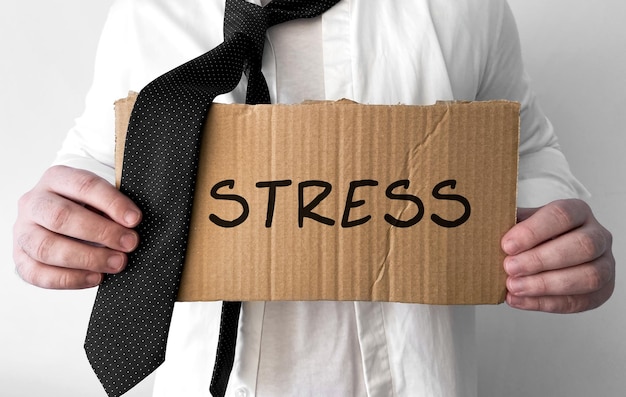 Un uomo d'affari arruffato alza un cartello di cartone con le parole Stress