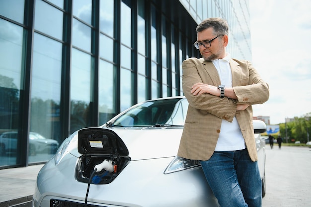 Un uomo d'affari carica un'auto elettrica