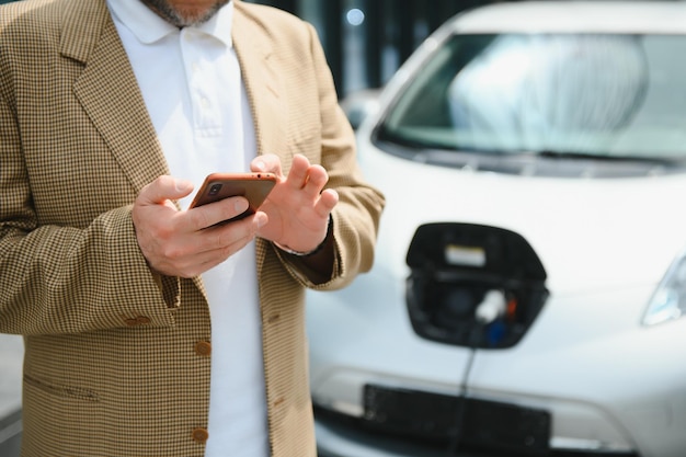 Un uomo d'affari carica un'auto elettrica