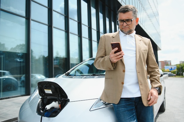 Un uomo d'affari carica un'auto elettrica