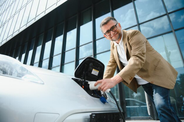 Un uomo d'affari carica un'auto elettrica