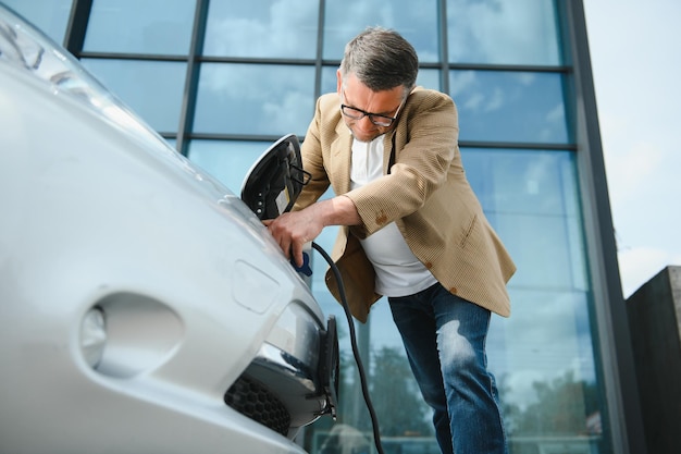 Un uomo d'affari carica un'auto elettrica